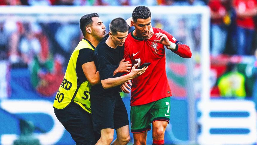 Two fans enter field for selfies with Cristiano Ronaldo during match at Euro 2024